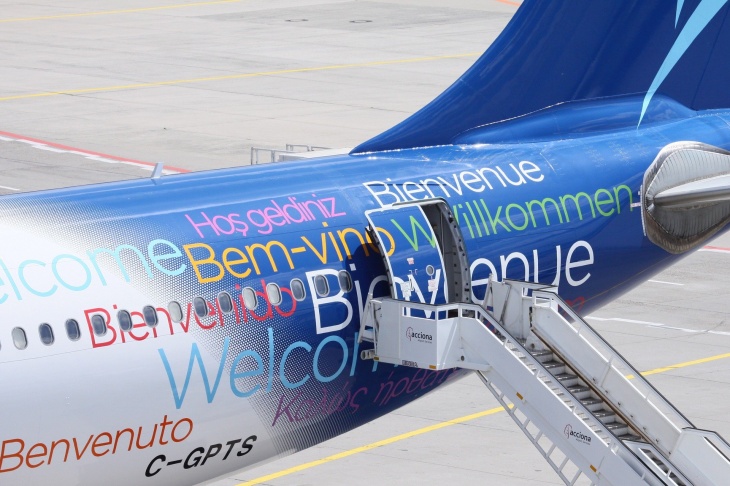 blaues Flugzeug mit der Aufschrifft "Welcome" in verschiedenen Sprachen