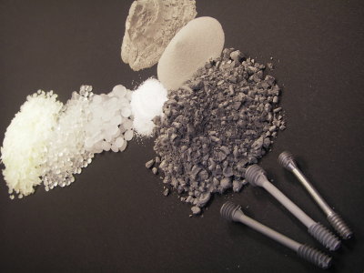 Metallpulver-Spritzgießen: Oben rechts die Metallpulver, links Polymerkomponenten, mittig das gemischte Granualt. Unten: Bauteil-Vorstufen sowie die fertige Mg-Ca-Knochenschraube rechts.